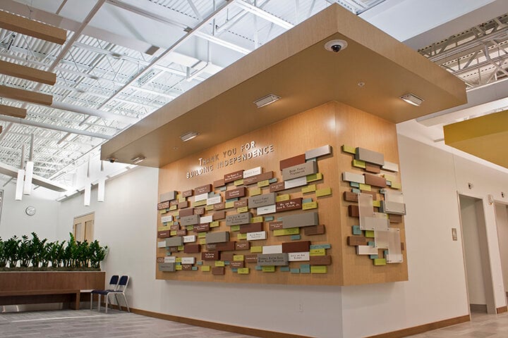 A wooden display wall with placards displaying major donor names